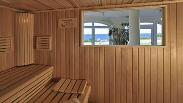 Un sauna avec des bancs en bois et une vue sur la mer par une fenêtre.