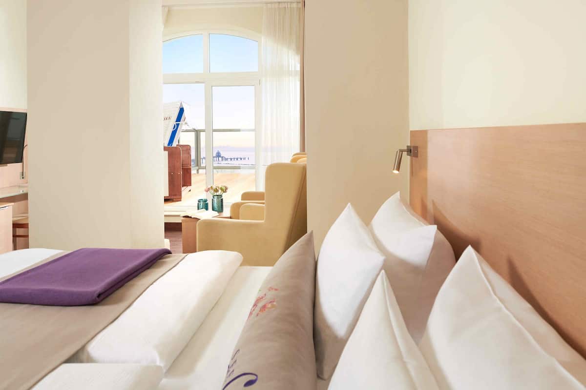A hotel room with a bed, a desk, and a view of the beach.