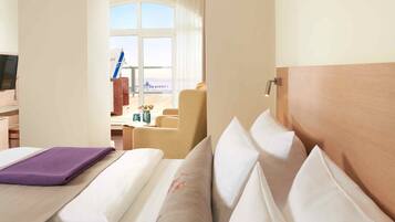 A hotel room with a bed, a desk, and a view of the beach.