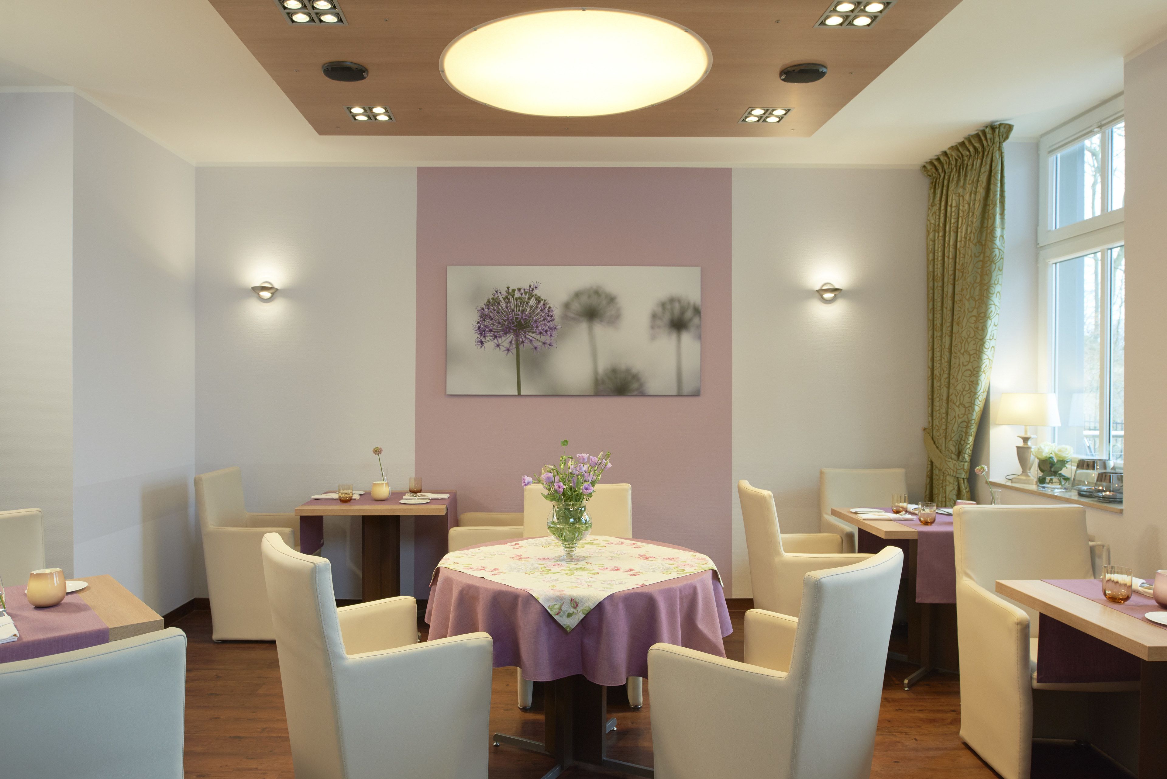 A dining area with round tables, chairs, and a central floral arrangement.