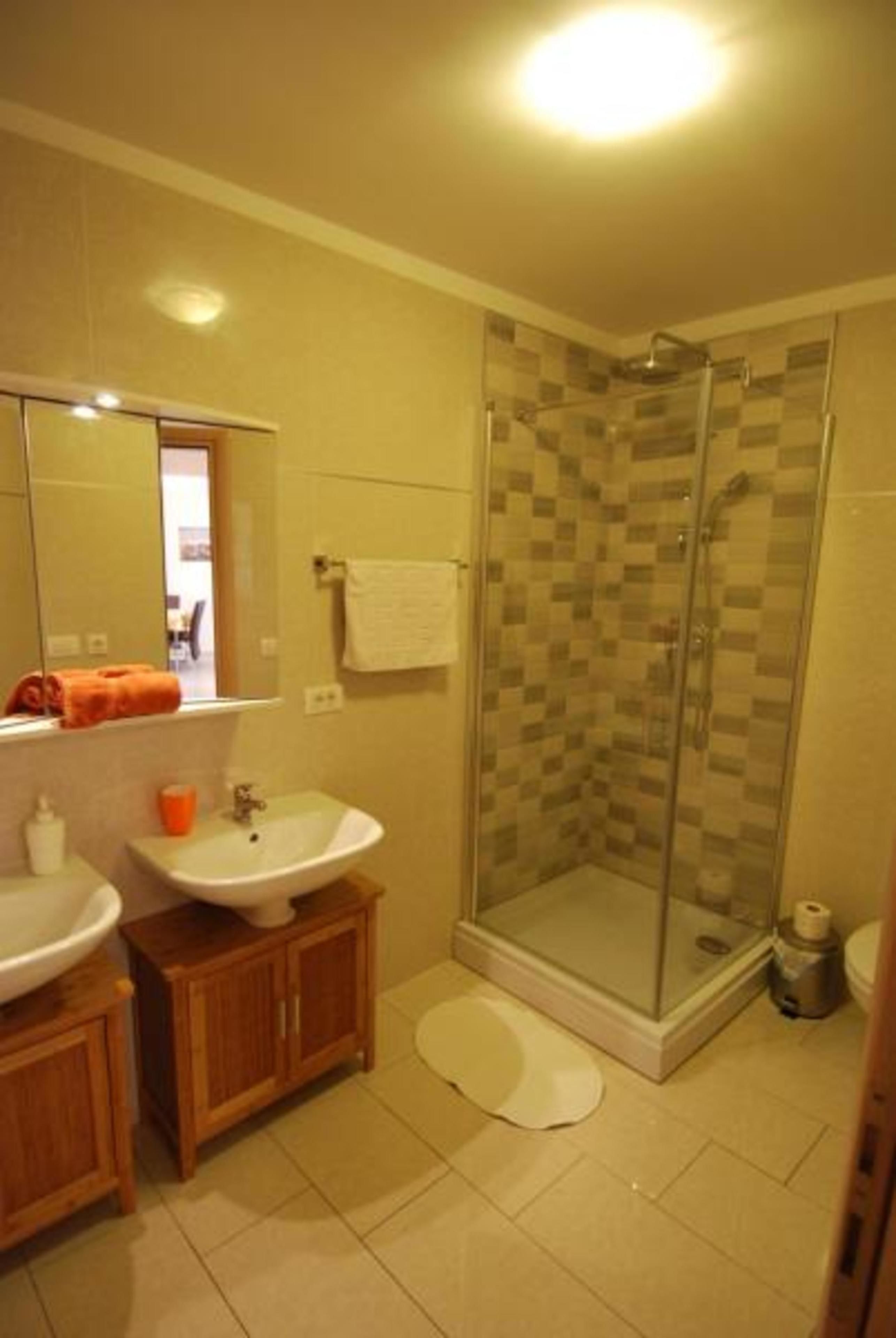 Un bagno con doccia vetrata, lavandino e specchio.