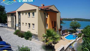 A two-story building with a swimming pool, a beach view, and a clear sky. - Soline Bay Seashore Residence (Dobrinj)