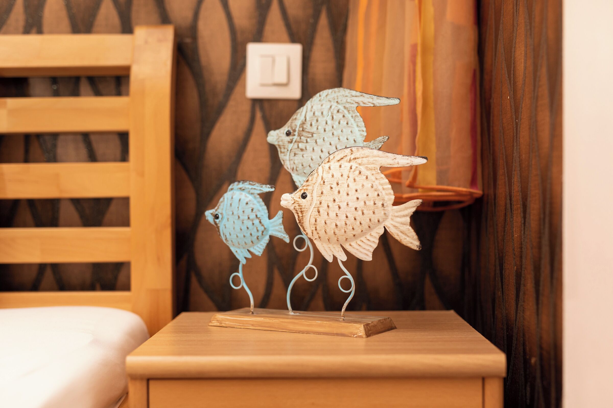A wooden bedside table with a metal fish sculpture.