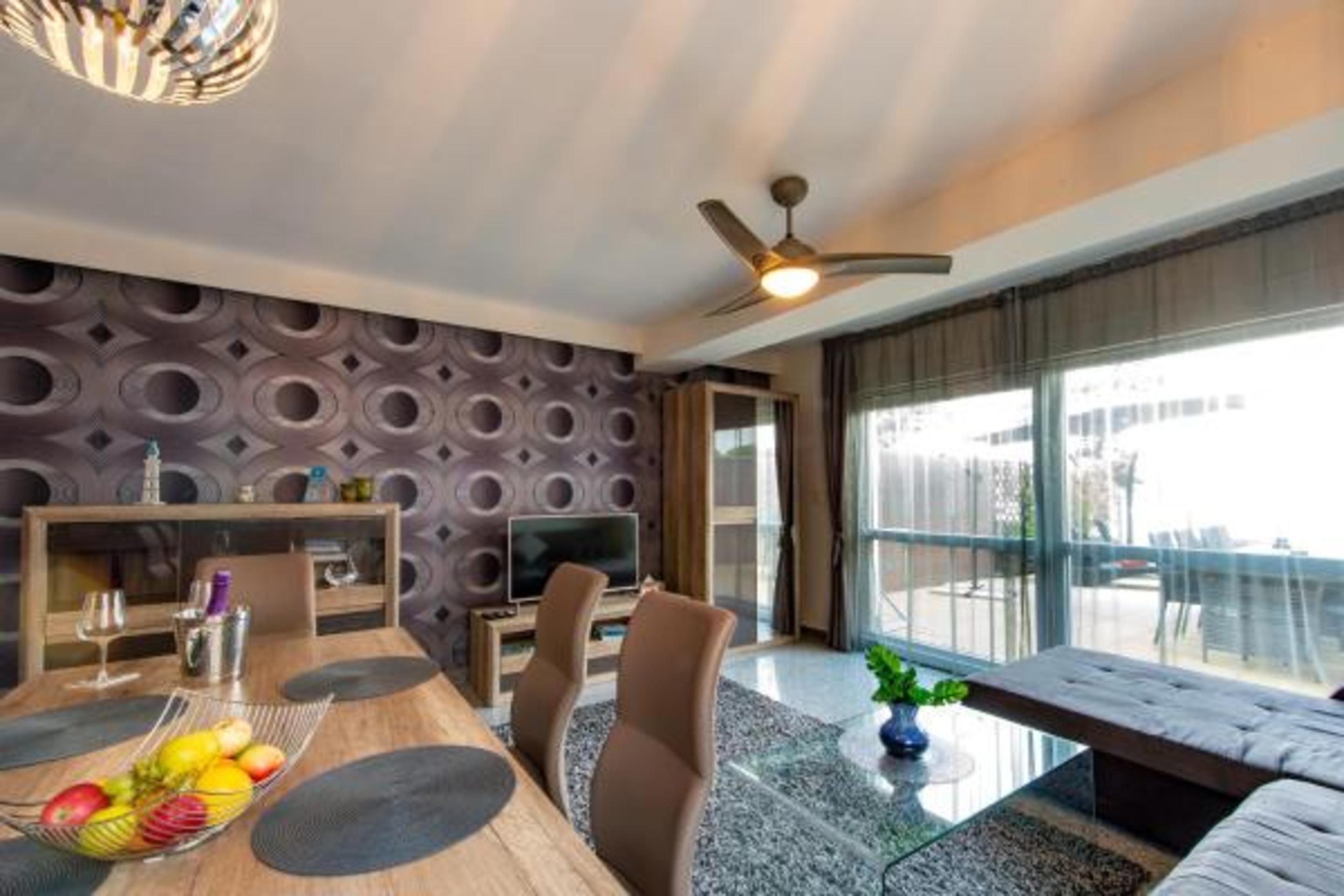 A modern living room with a dining area, a television, and a large window with a view.