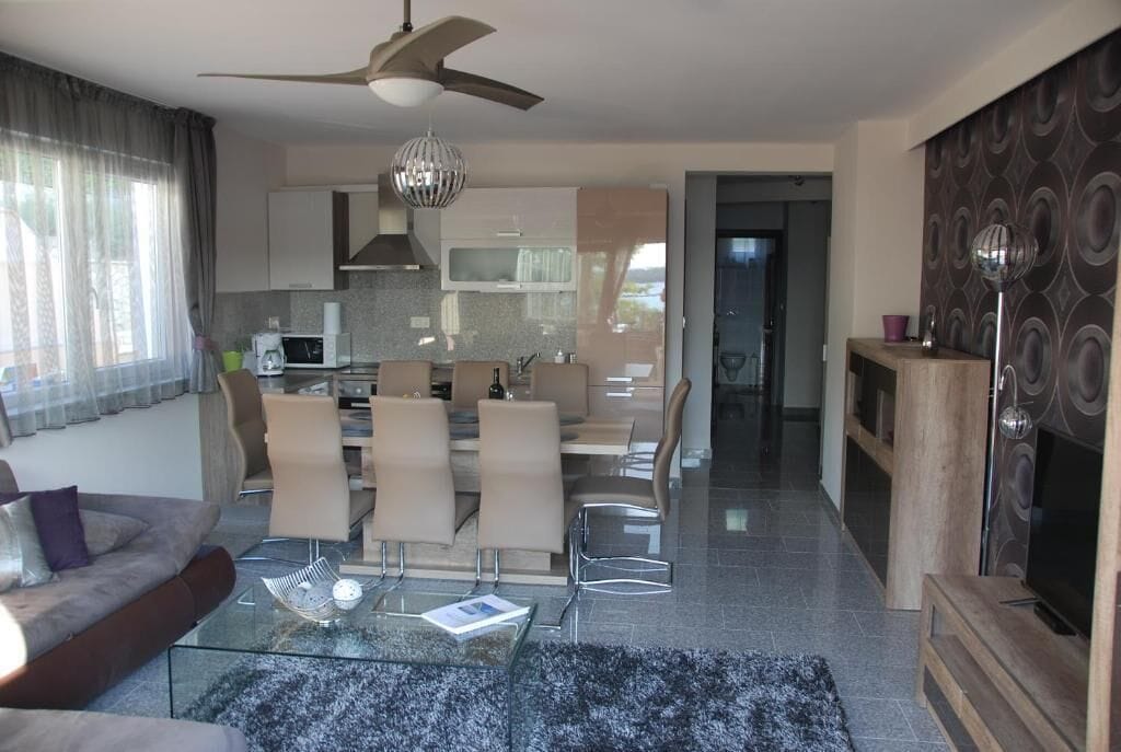 A modern living room with a glass coffee table, a sofa, and a TV stand.