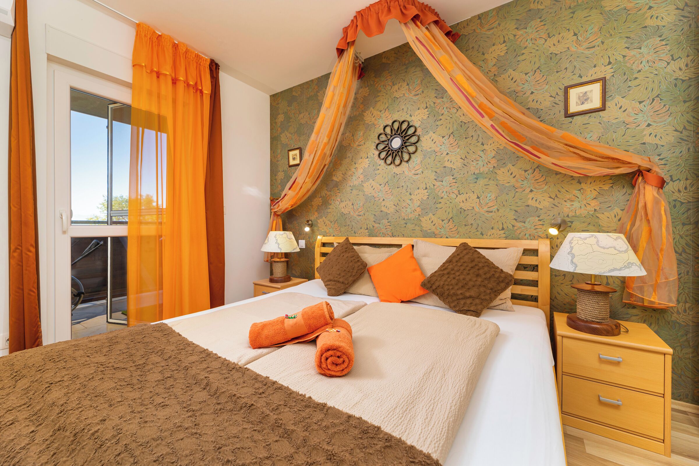 A bedroom with a bed, a nightstand, a wall clock, and a window with curtains.