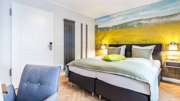 A bedroom with a bed, a chair, a nightstand, and a wall painting.