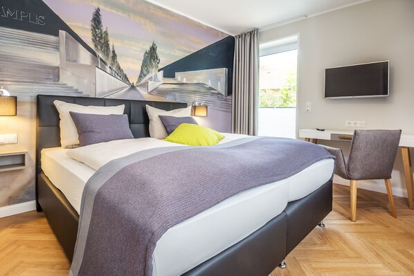 A modern hotel room with a large bed, a desk, and a TV. - Burghotel Lingen (Lingen)