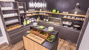 A modern kitchen with a central island, equipped with various appliances and food items. - Burghotel Lingen (Lingen)
