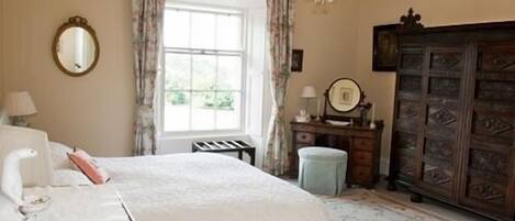 A bedroom with a bed, a dresser, a mirror, and a chandelier.