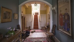 A grand hallway with a staircase, a chandelier, and a large framed painting on the wall. - Lough Bawn House (Collinstown)