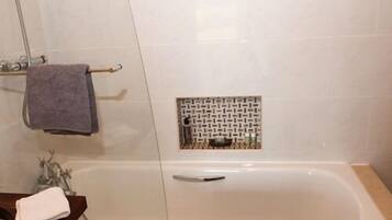 Un baño con bañera, toallero y zona de ducha.