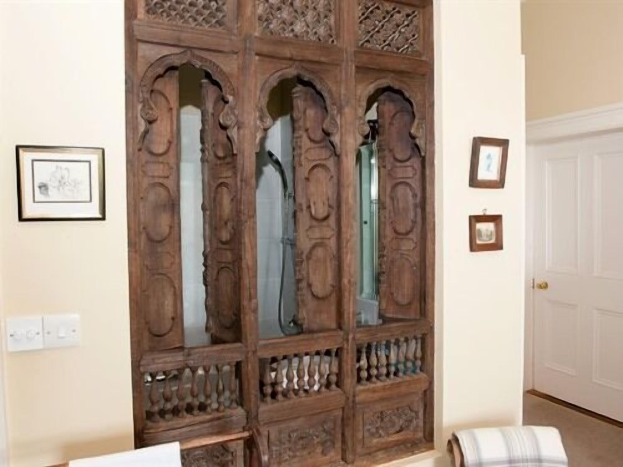 A wooden wardrobe with intricate carvings and a glass door.