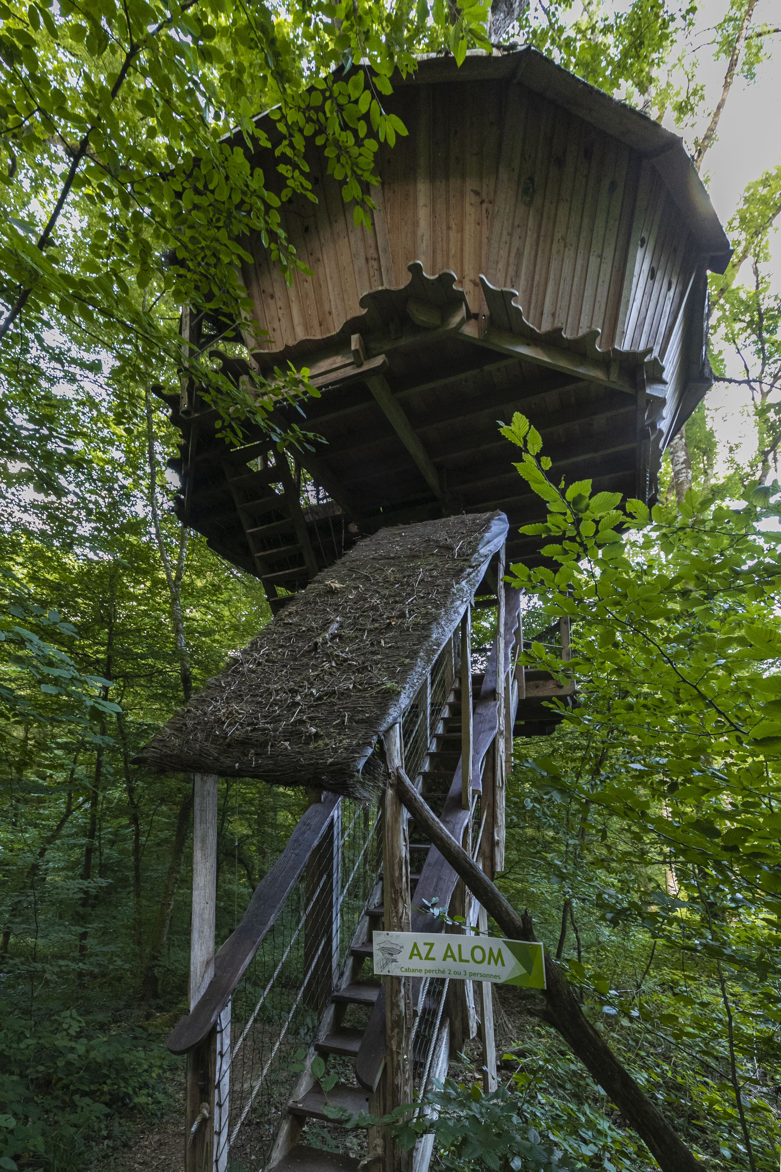 A wooden observation tower with a staircase and a sign reading "AZ ALOM".