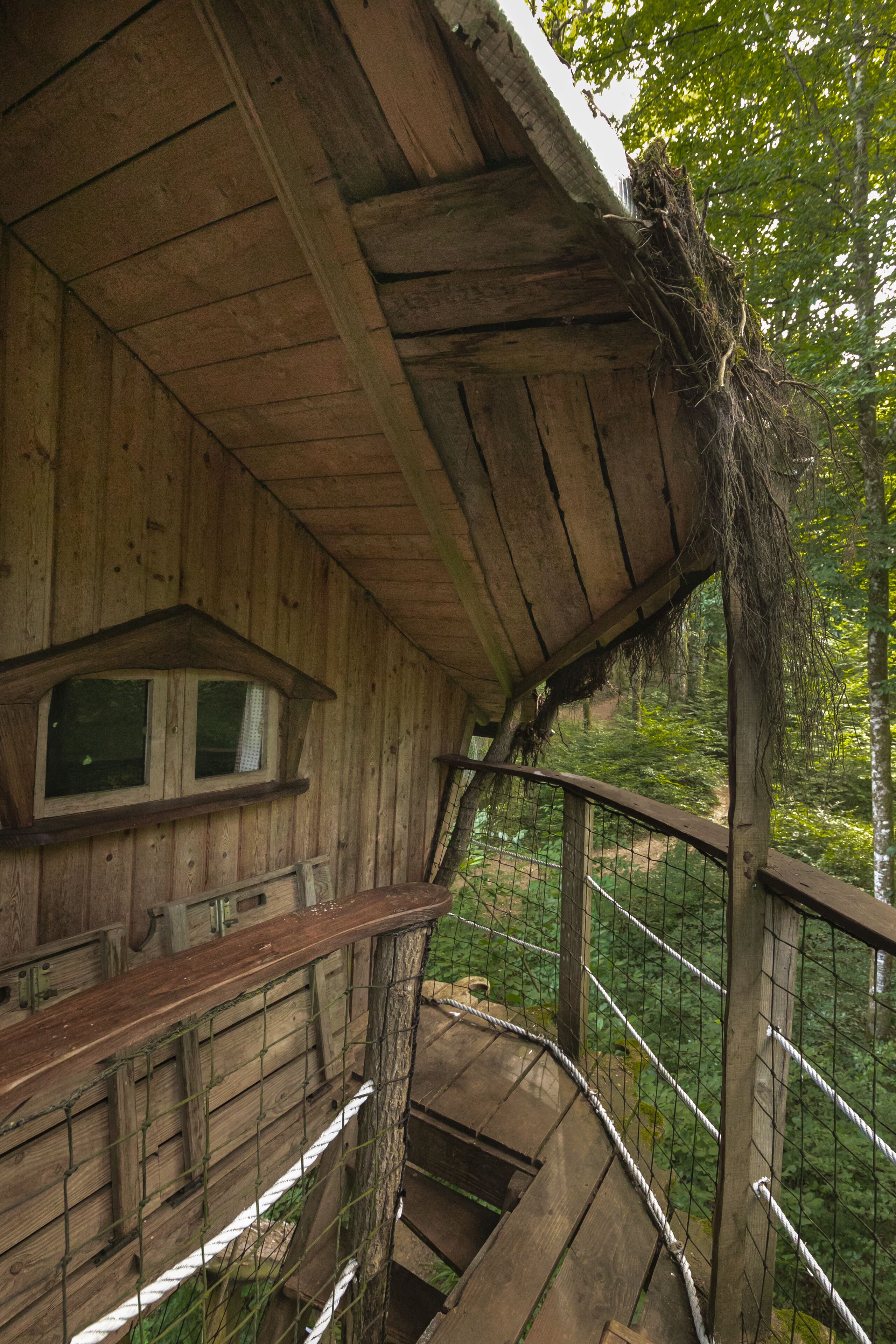 Eine Holzhütte mit Fenster und einer Treppe, die zu einem Balkon führt.