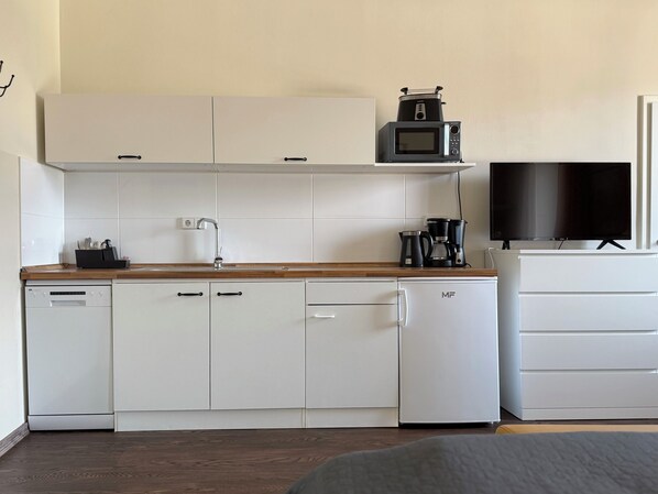 A compact kitchen with a microwave, coffee maker, and a dishwasher. - Apartments Fichtelberger Blick (Oberwiesenthal)