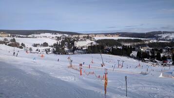 Ein Skigebiet mit mehreren Pisten, Skiliften und einer Stadt im Hintergrund.
