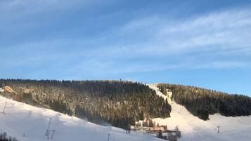 A snowy ski slope with a ski lift and a building in the background.