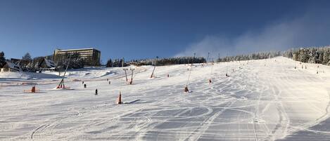 A ski slope with marked trails and a building in the background.