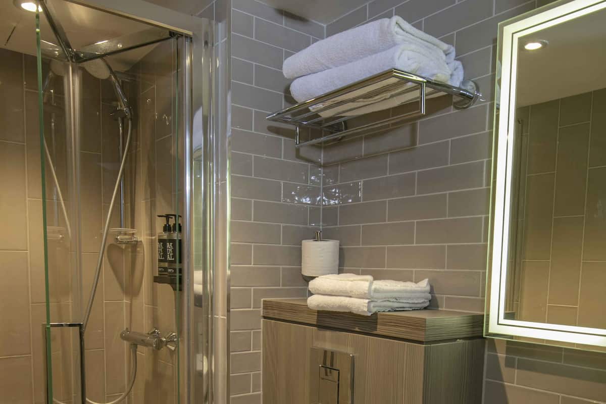 Une salle de bain moderne dotée d’une douche à parois de verre, de toilettes blanches et d’un lavabo avec un plan de travail en marbre.