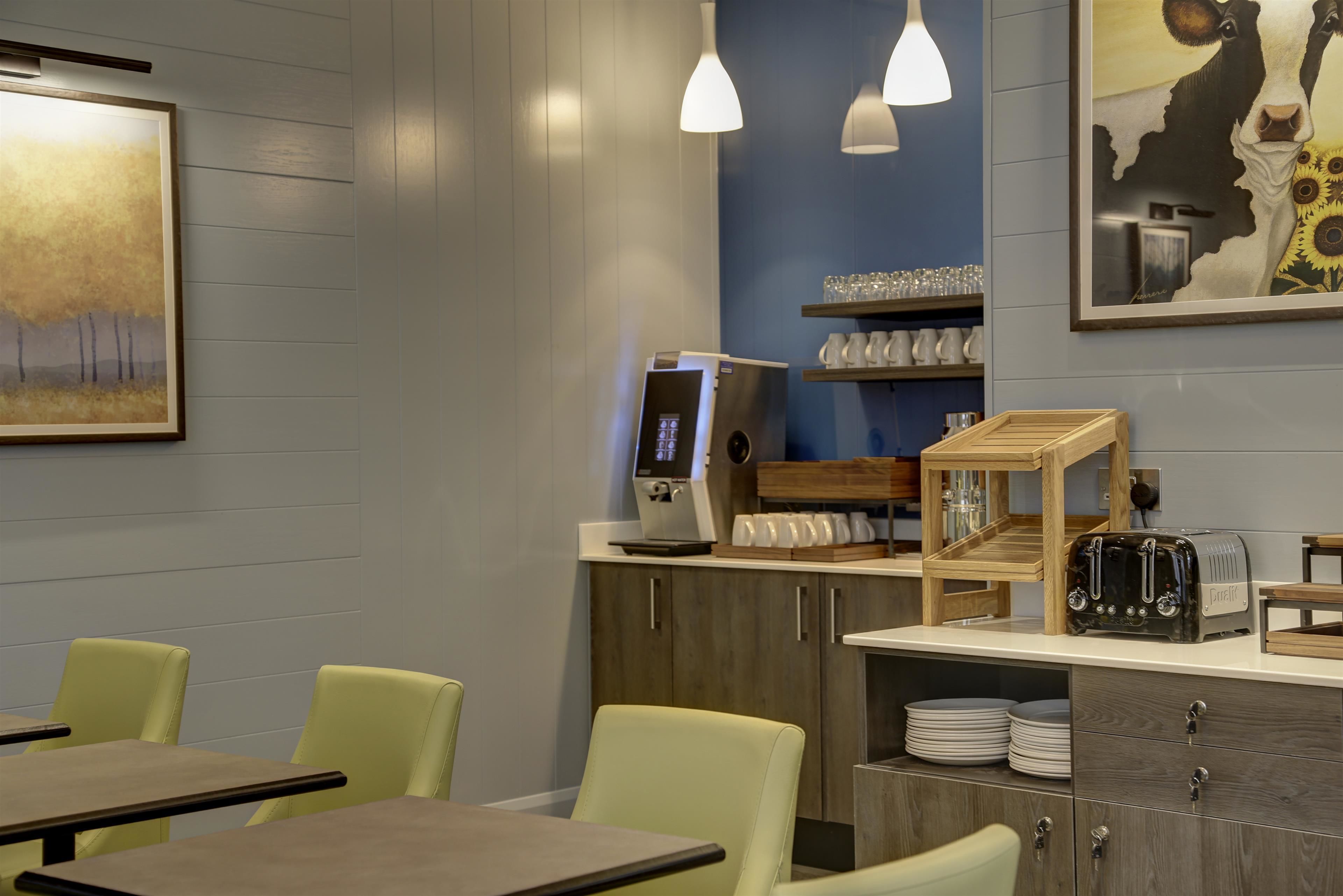 Un restaurant au décor moderne, avec des tables et des chaises en bois, une machine à café et un grille-pain sur le comptoir.