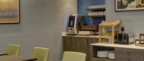 Un restaurant au décor moderne, avec des tables et des chaises en bois, une machine à café et un grille-pain sur le comptoir.