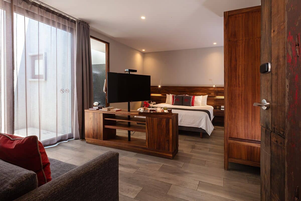 A hotel room with a bed, a TV, a wooden cabinet, and a sofa.