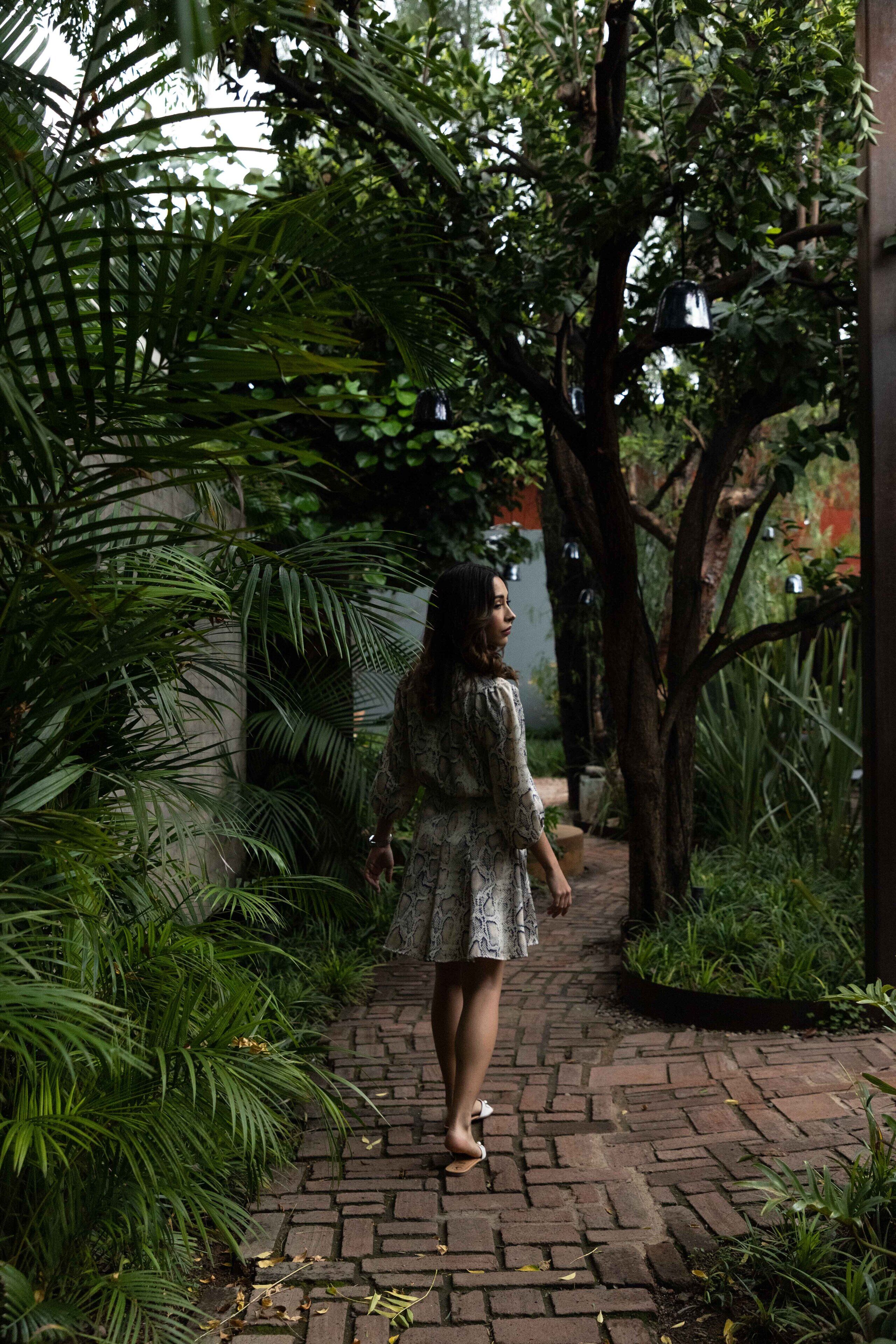 A person walking on a brick pathway surrounded by lush greenery.
