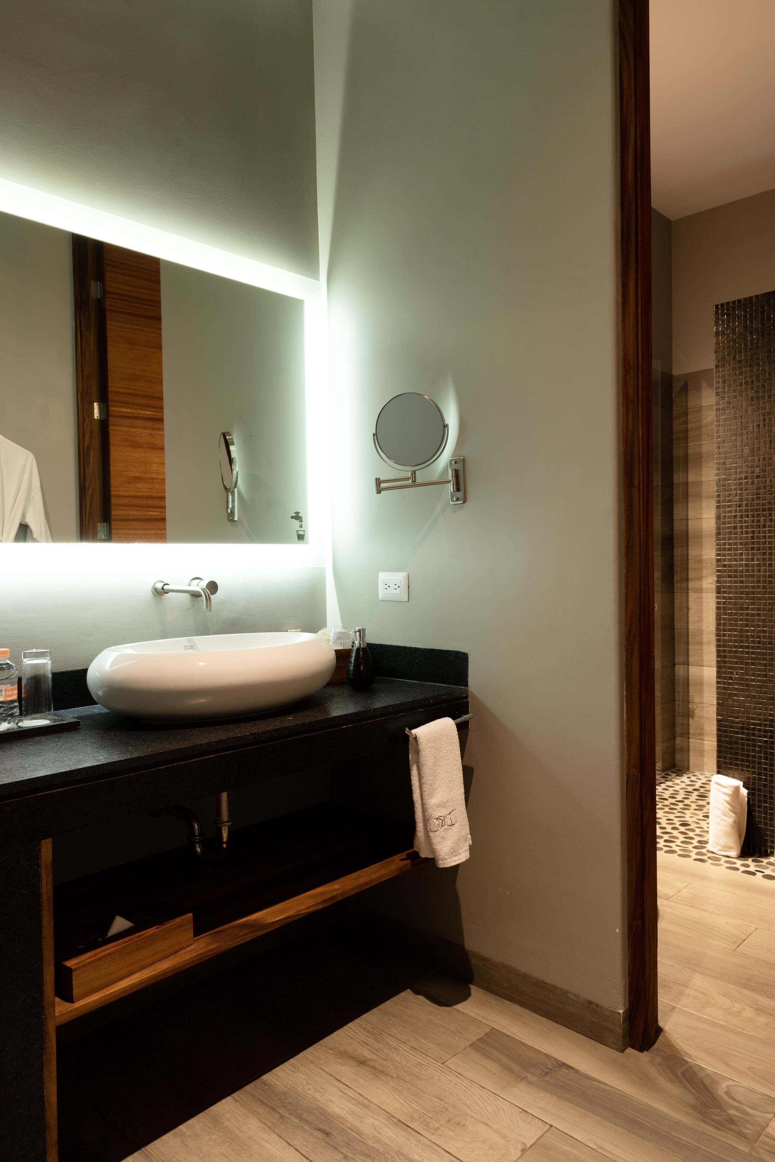 A modern bathroom with a large oval sink, a mirror, and a towel rack.