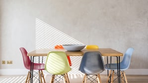 Un coin repas avec une table en bois et des chaises colorées.