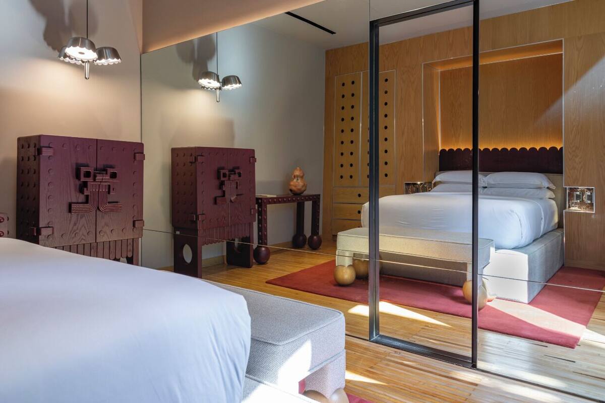 Une chambre moderne avec un grand lit, une cloison en verre et une tête de lit en bois.