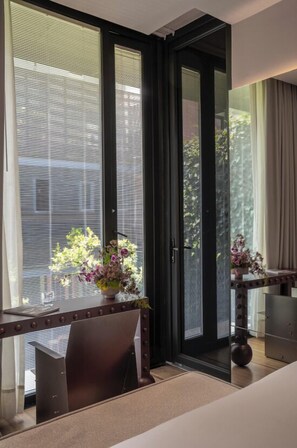 A modern room with a large sliding glass door leading to a balcony, a wooden table with a vase of flowers, and a chair.
