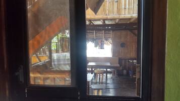 A wooden interior with a dining area, a staircase, and a view of the outside.