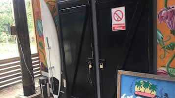 A hotel entrance with a black door, a surfboard leaning against it, and a sign prohibiting smoking.