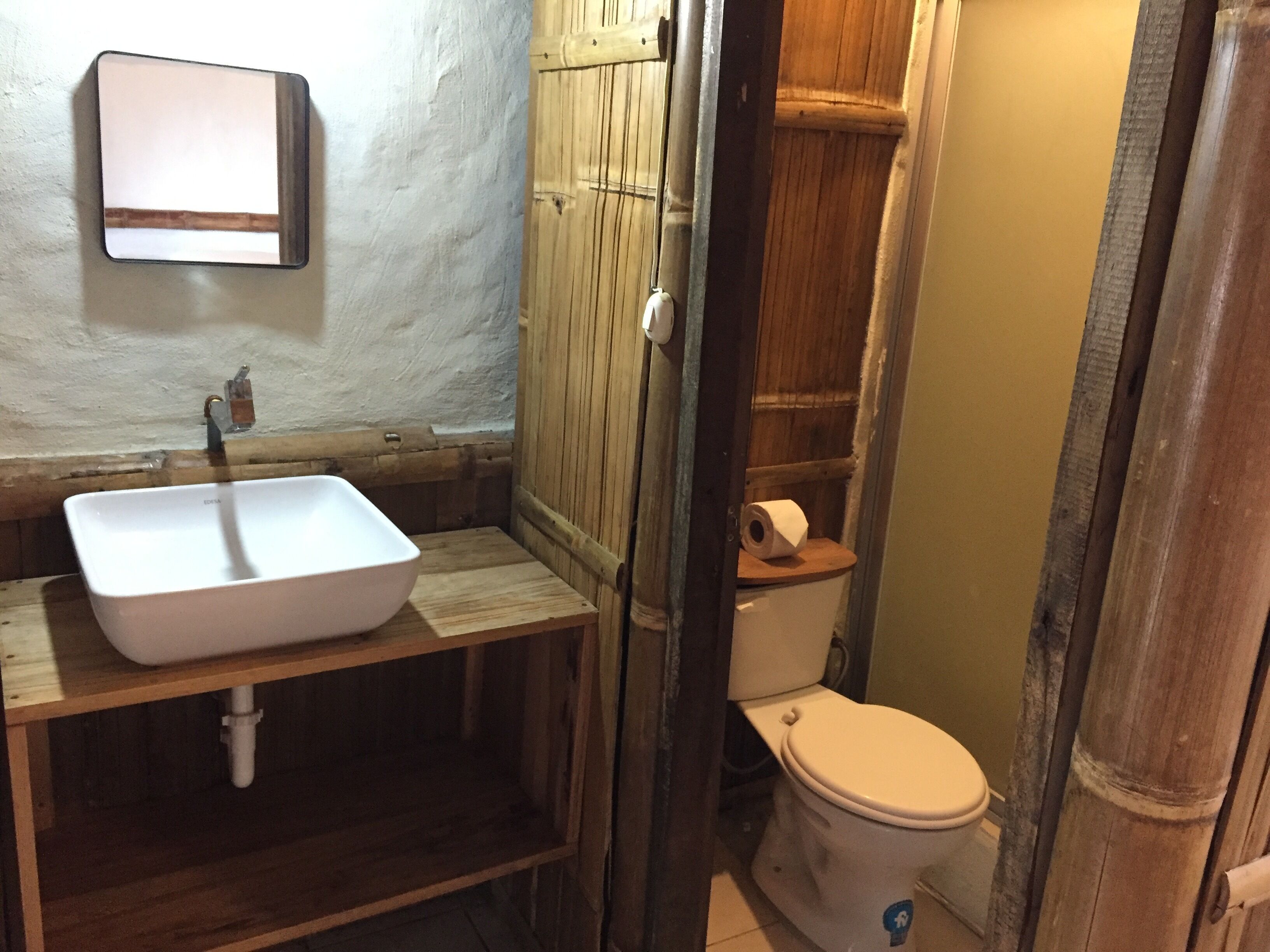 A bathroom with a wooden vanity, a white sink, and a toilet.