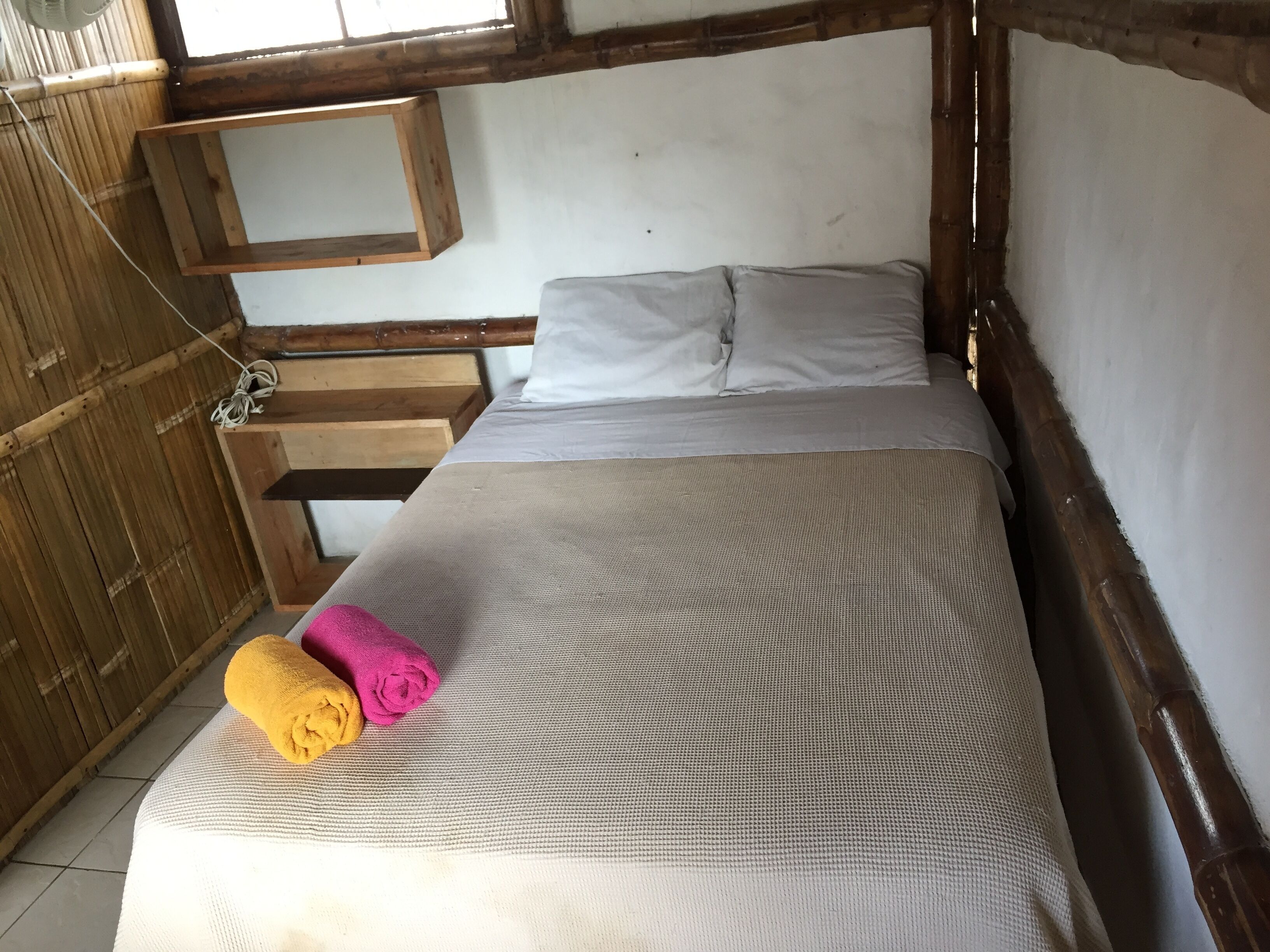 A room with a bed, wooden headboard, and a small wooden shelf.