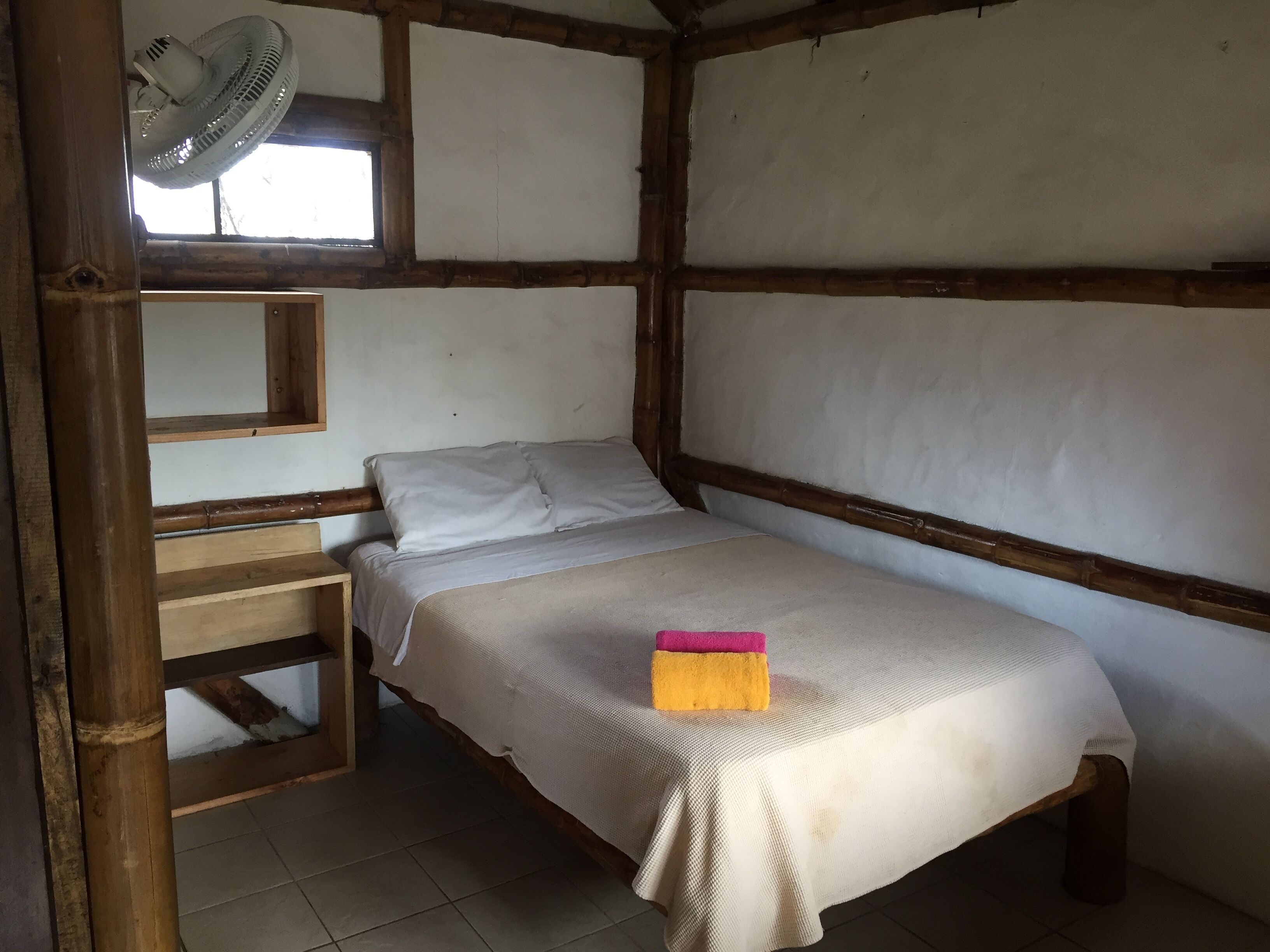 A single bed in a room with a wooden frame and a window.