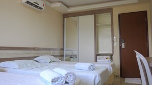 A hotel room with two beds, a large mirror, a wooden headboard, a wardrobe, and an air conditioning unit. - Altiplano Hotel (João Pessoa)
