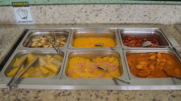 Ein Buffet mit verschiedenen Speisen, darunter Obst, Reis und ein Currygericht.