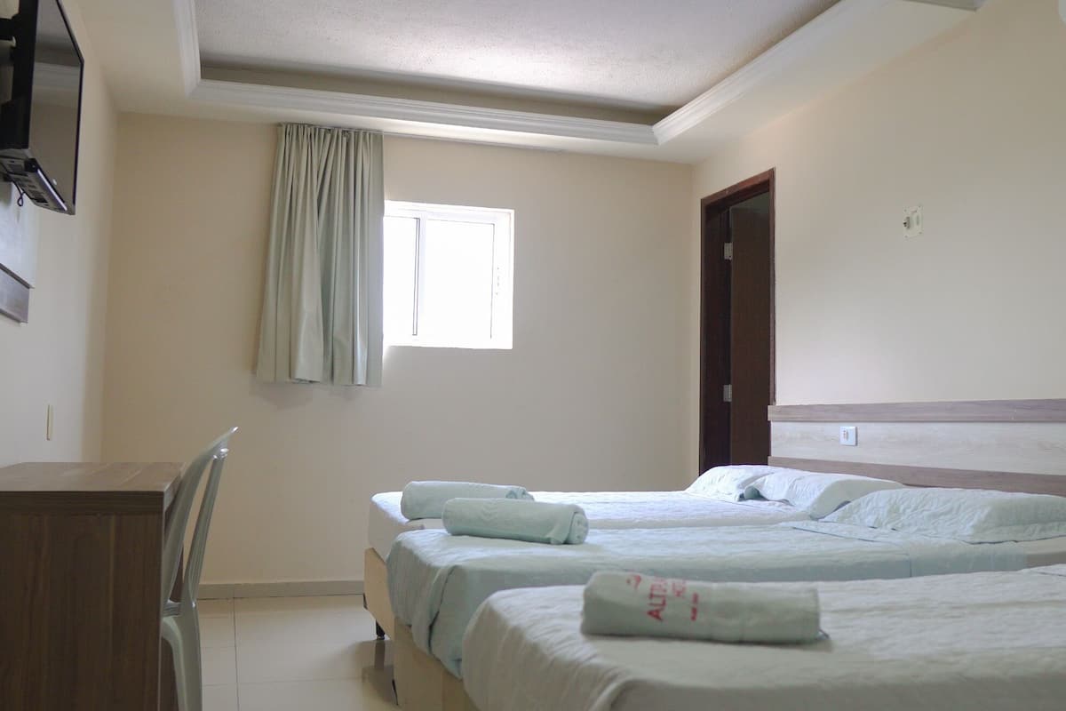 Une chambre d’hôtel avec deux lits, un bureau et une fenêtre avec des rideaux.