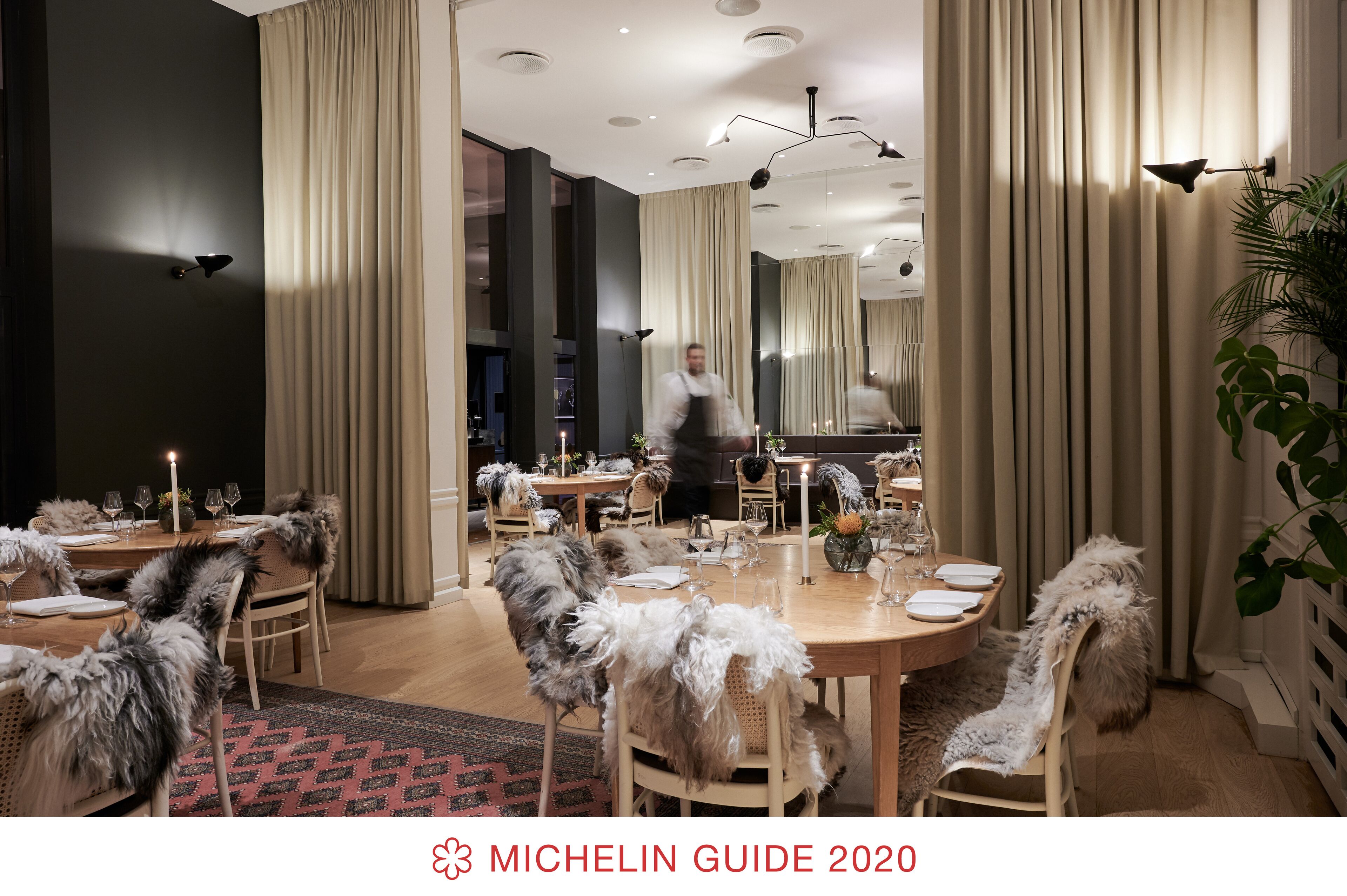 A dining area with round tables, feathered chairs, and a chandelier.
