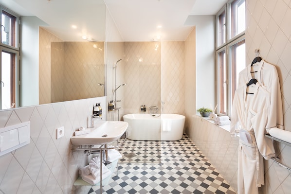 Un baño moderno con una bañera independiente, un tocador con lavamanos y un espejo grande.