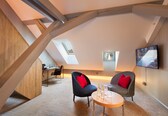 A modern loft-style room with a sloped ceiling, a dining area, and a seating area with two chairs and a table.