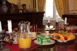 A dining table set with fruit, a pitcher of orange juice, and candles.