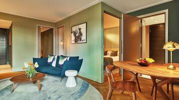 A modern living room with a blue sofa, a round coffee table, and a dining area with a wooden table and chairs.