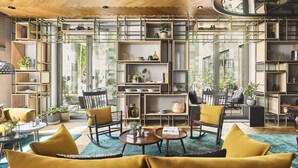 A modern living room with a sofa, chairs, a coffee table, and a pool table. There are shelves with plants and decorative items. - Hyatt Regency Amsterdam (Amsterdam)