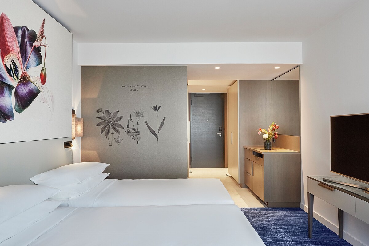 A modern hotel room with a large bed, a desk, and a TV.