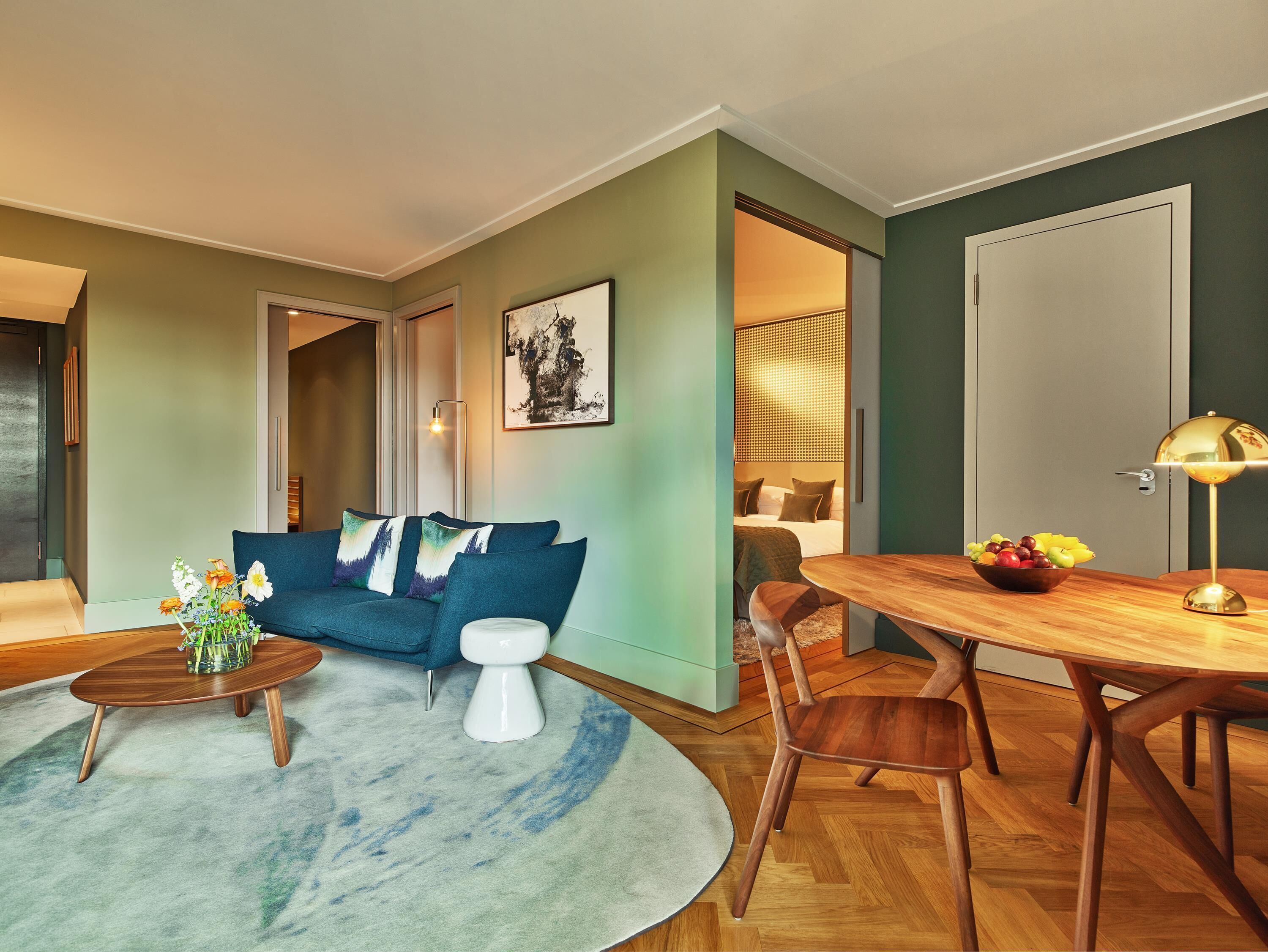 Un salon moderne avec un canapé bleu, une table basse ronde et une table à manger avec des chaises.