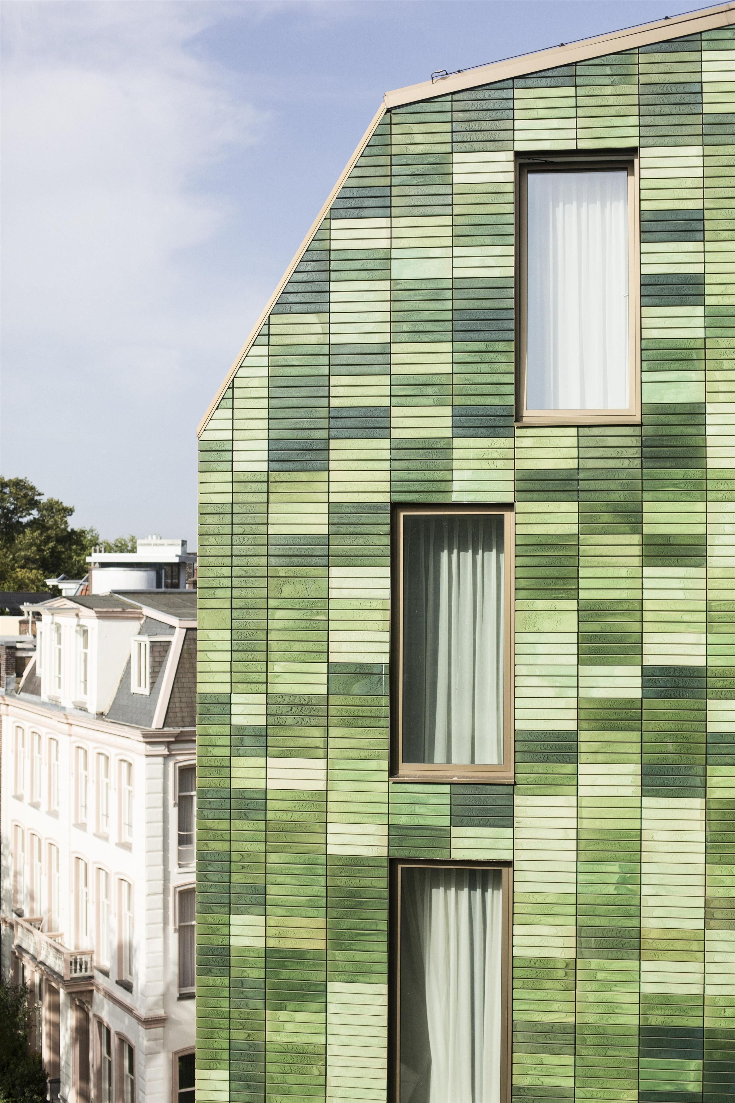 A modern building with a green facade and multiple windows.