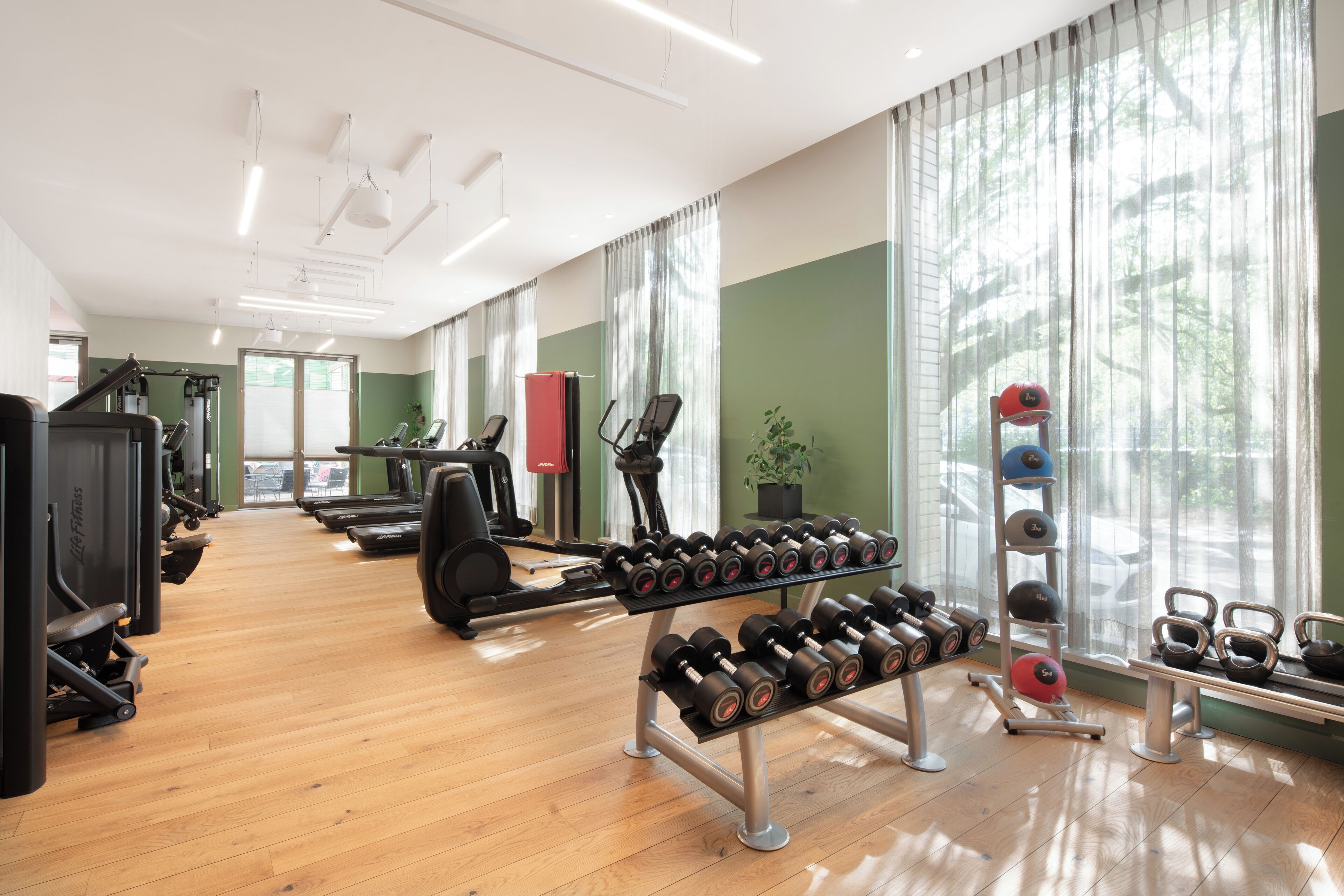 A gym with exercise equipment, treadmills, and dumbbells.
